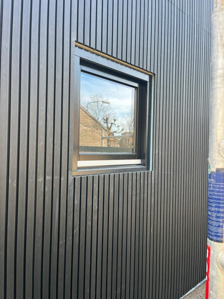 Raam in de donkere gevelbekleding van de schuur