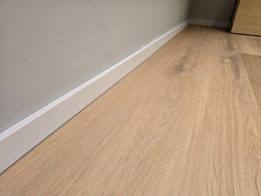 Detail of wood-effect flooring and white skirting at Rolife Rotterdam